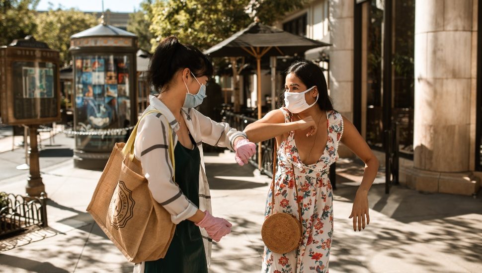 people in masks elbow bump