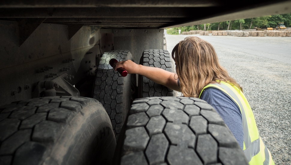 woman with flashlight under truck