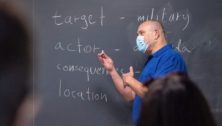 man teaching at blackboard with mask on