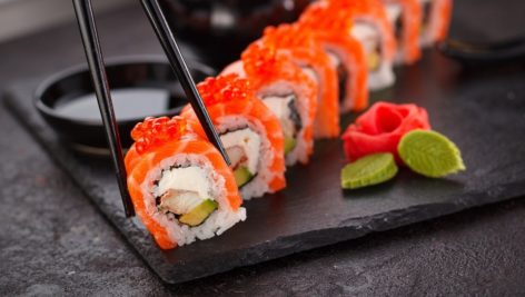 A sushi roll laid out on a black slate