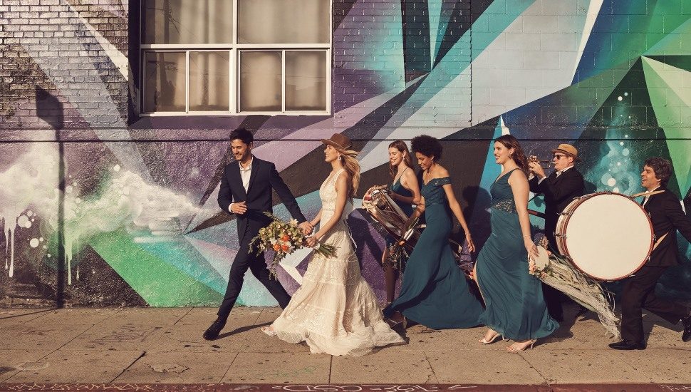Wedding party walking down the sidewalk.