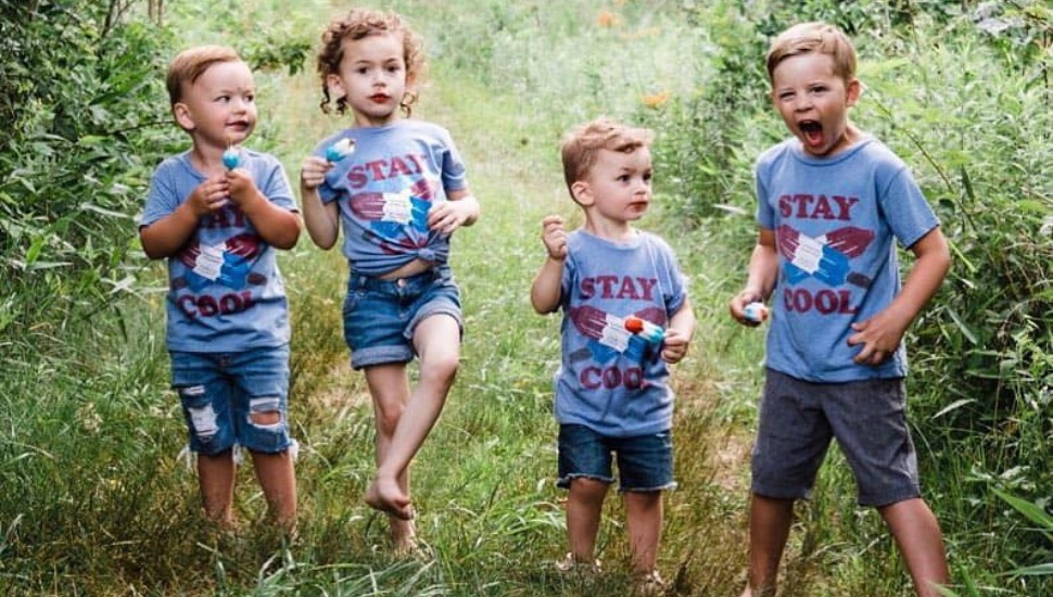 four kids outside in grass.