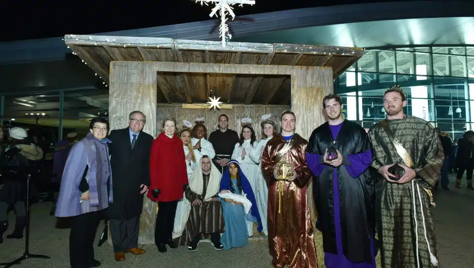 A group gathers in front of a manger scene at a past Live Nativity event at Neumann University