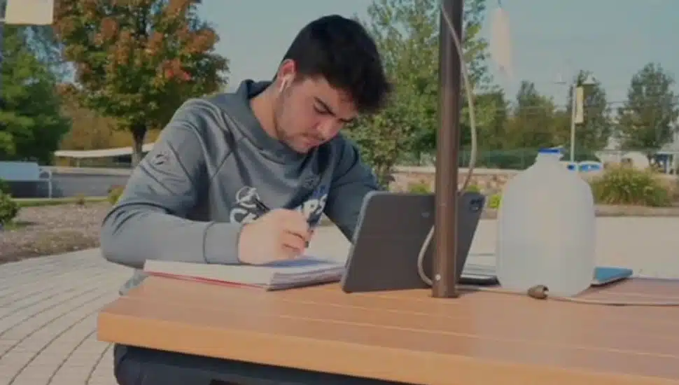 Neumann University student at an outside table working on his laptop.