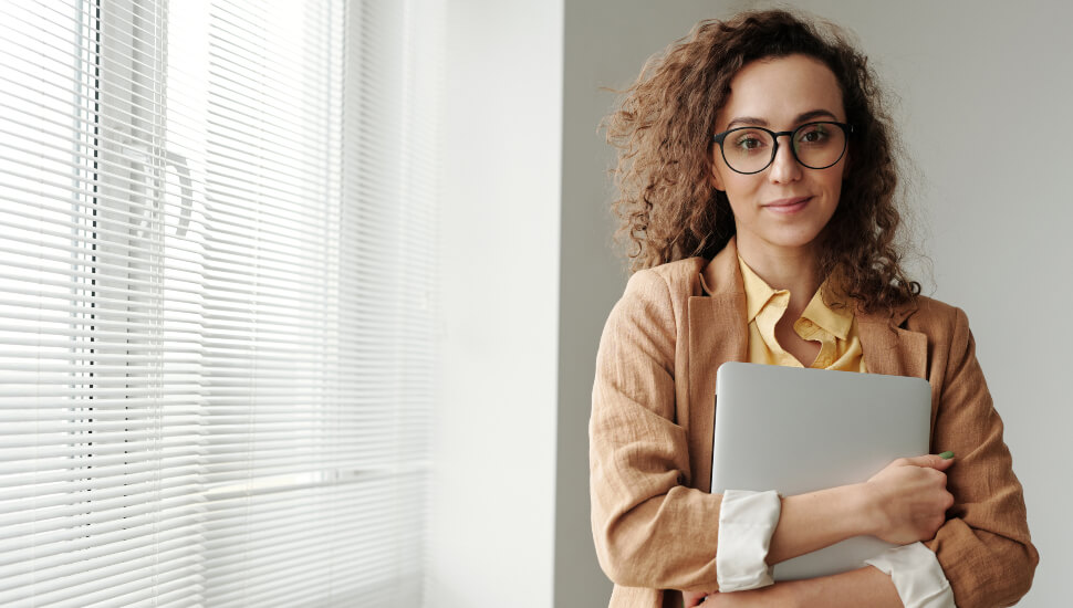 Woman in an office carrying her laptop