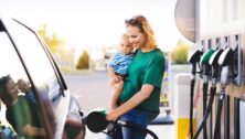 Woman-holding-a-child-pumping-gas
