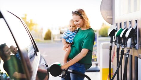 Woman-holding-a-child-pumping-gas