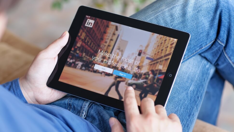 Young man logging into LinkedIn on his ipad