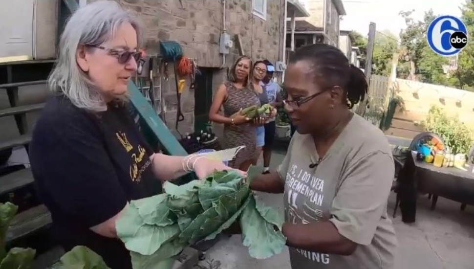 Jeri Brockington hands produce from her garden to a neighbor