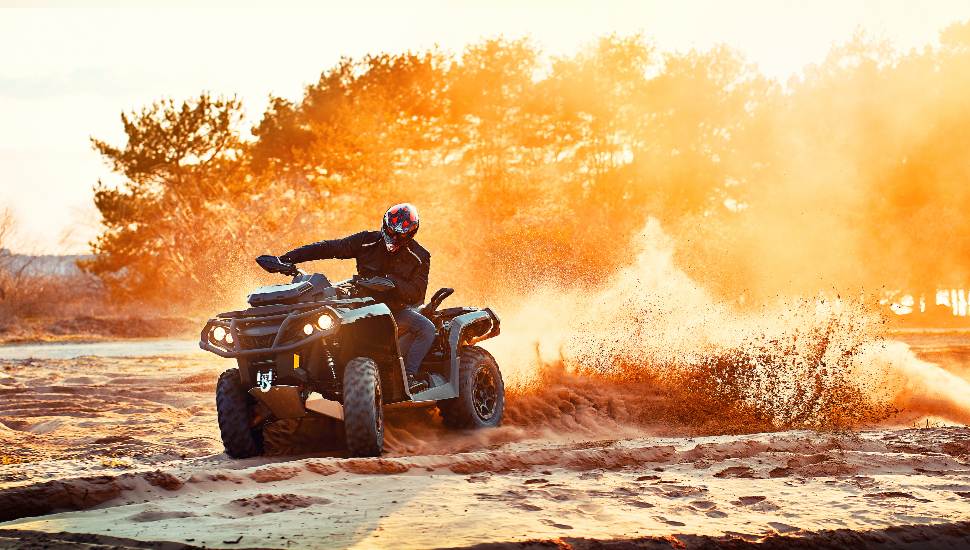 Teen riding ATV in sand dunes making a turn in the sand