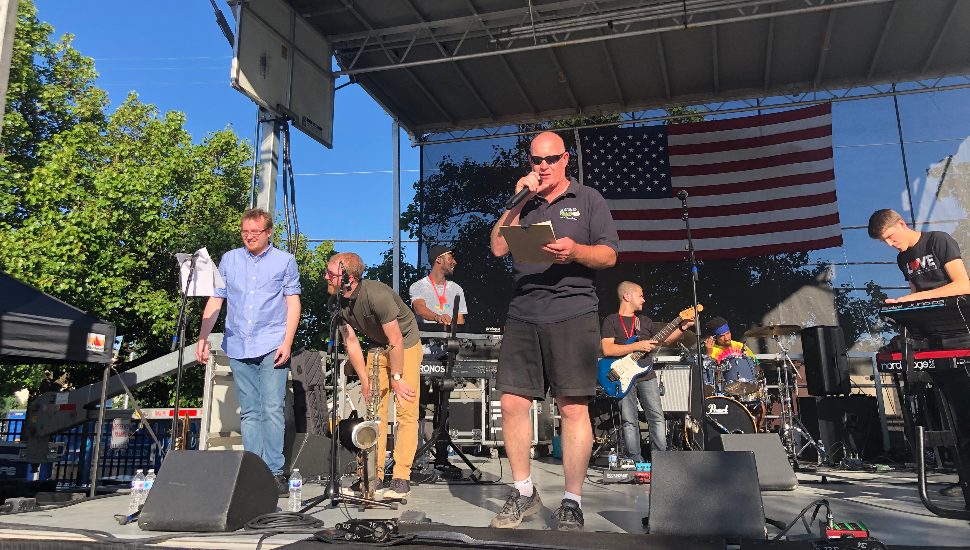 man on stage in front of a flag