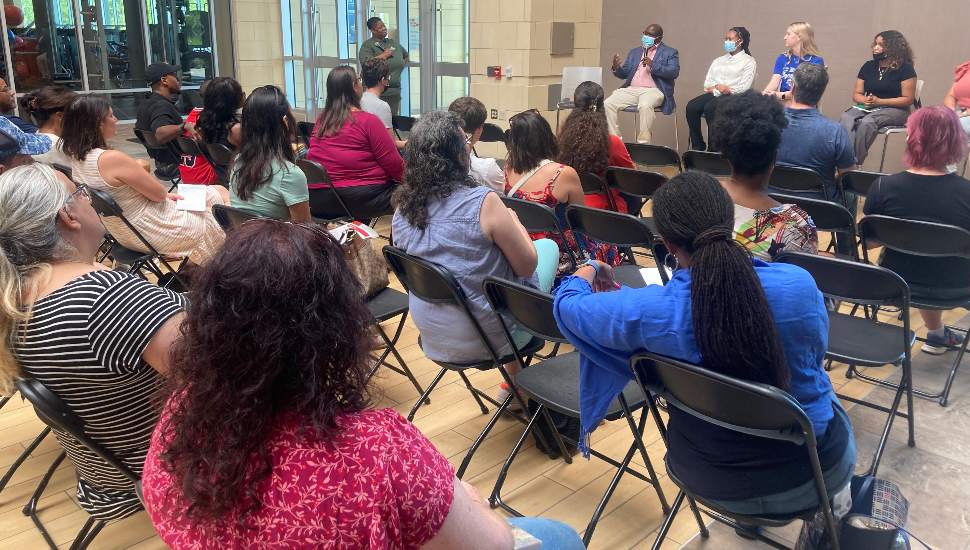 people in chairs listening to a panel of speakers
