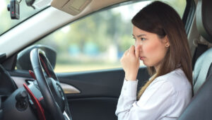 woman holding nose in car