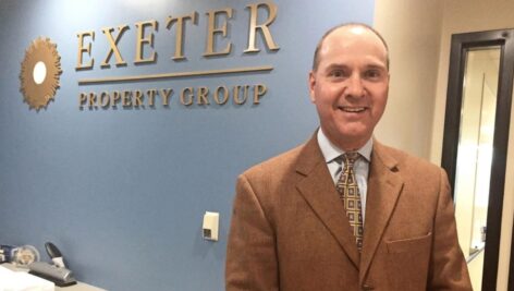 Ward Fitzgerald standing in front of Exeter Property Group sign inside