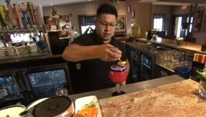 man squeezing fruit into a drink