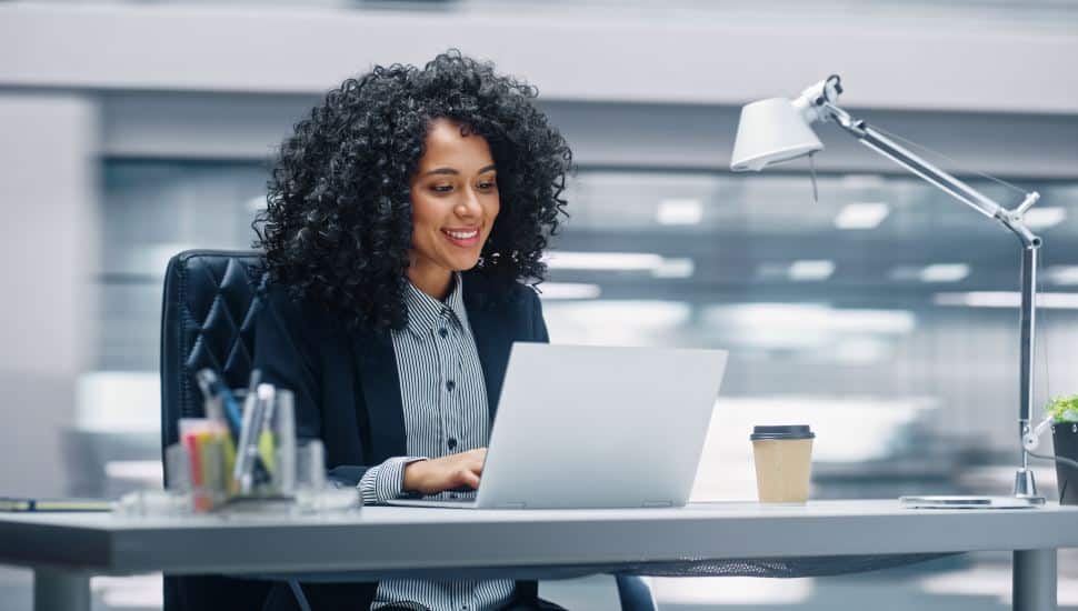 Modern Office: Businesswoman Sitting at Her Desk Working on a Laptop Computer.
