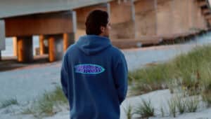 man in blue WoodLuck hoodie by a bridge