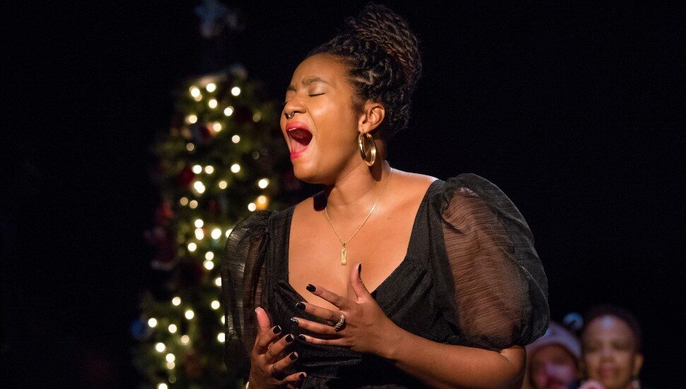 The Color Purple cast member singing in front of little lights