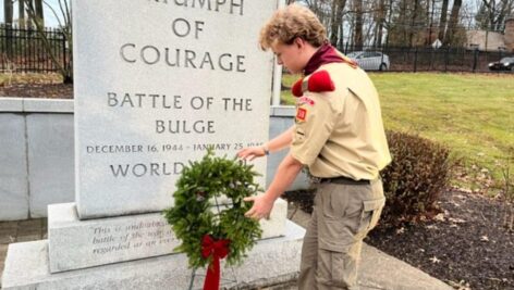 Shane Simpson, Boy Scout from Devon Troop 50, places a wreath at the Battle of the Bulge monument on the campus of Valley Forge Military Academy & College. The wreath is one of several donated to VFMAC.