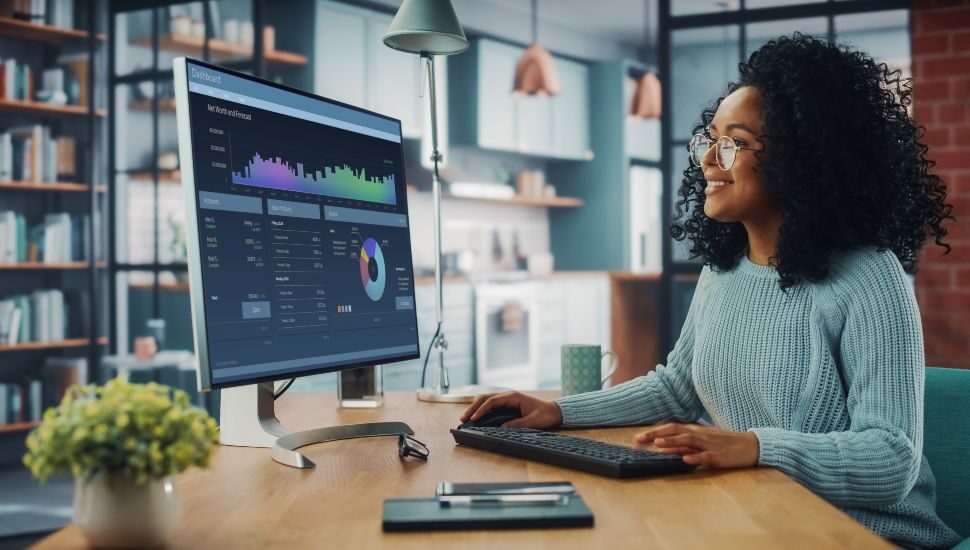 Latina Female Specialist Working on Desktop Computer at Home Living Room while Sitting at a Table.