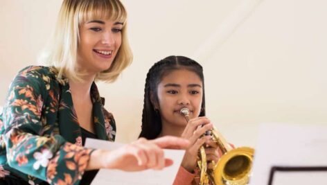 Teacher Helping Female Student To Play Trumpet In Music Lesson