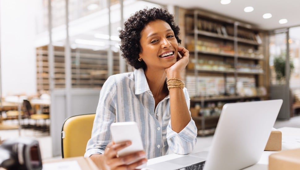 Successful online store owner smiling at the camera while working in a warehouse.
