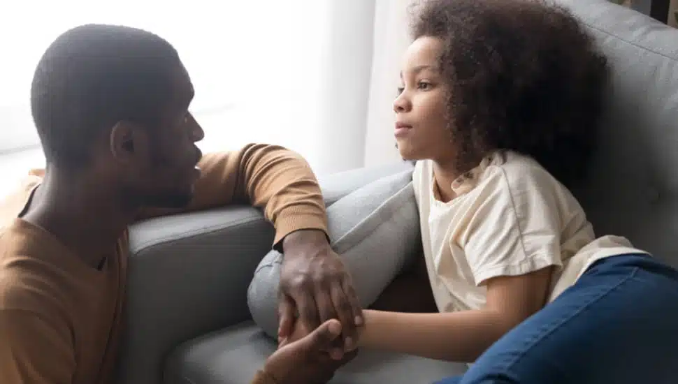 A father talking gently to his seated daughter