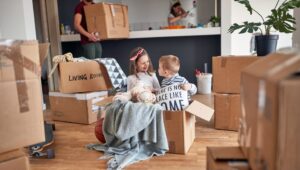 Two kids playing in boxes as their parents move into a new house
