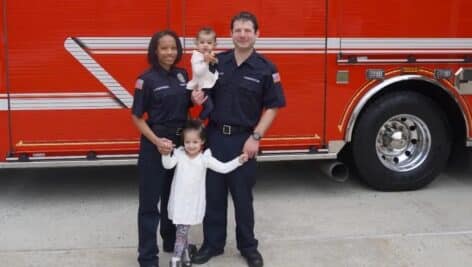 Jennifer Kingsberry, with her husband and two young daughters in front of fire truck