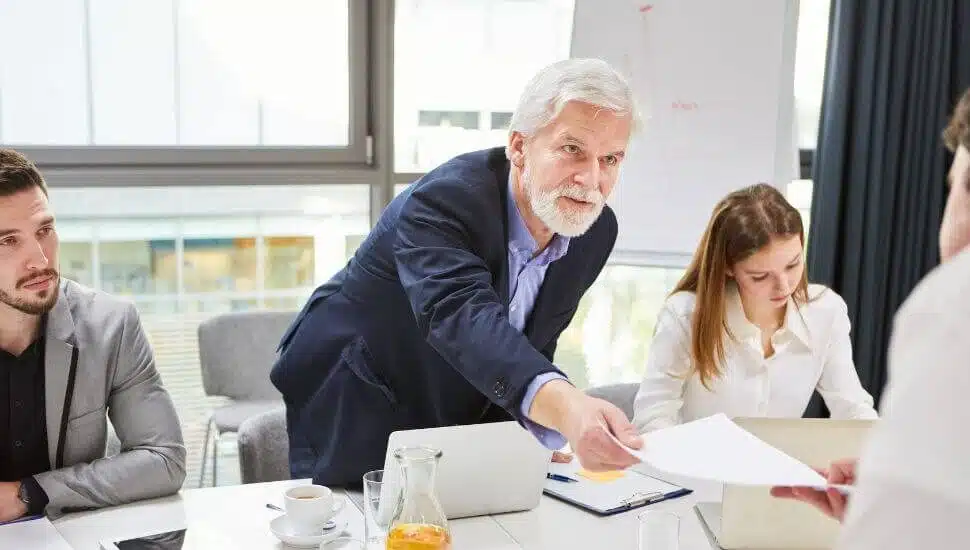 Man reaching across a conference room table.