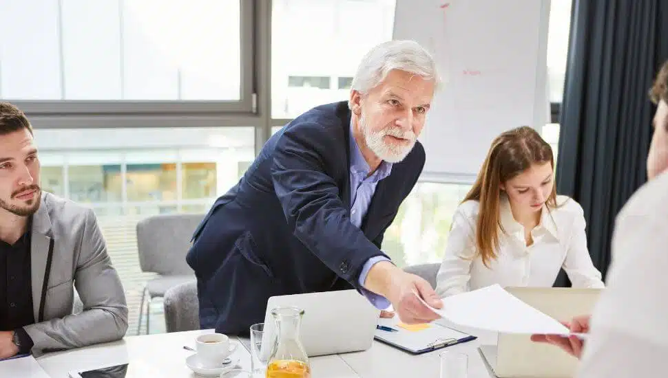 Man reaching across a conference room table.