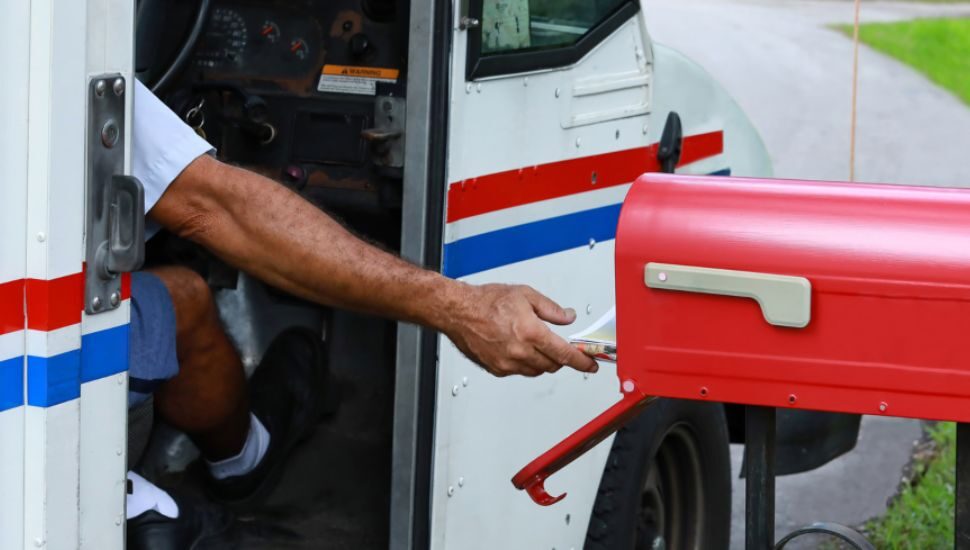 USPS carrier putting mail in mailbox