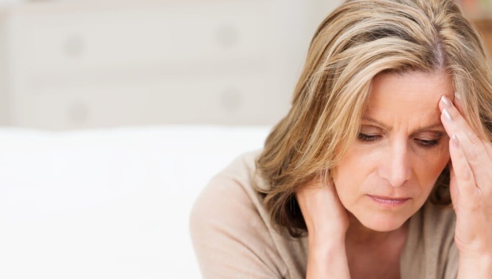 A woman with a hand to her forehead looking stressed