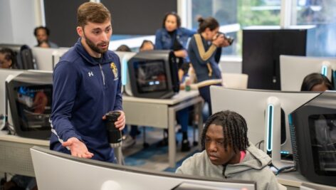 Derek Bosworth, coach of Neumann’s esports teams, explains video game options to a student from Chester Charter Scholars Academy at Neumann's esports lab.