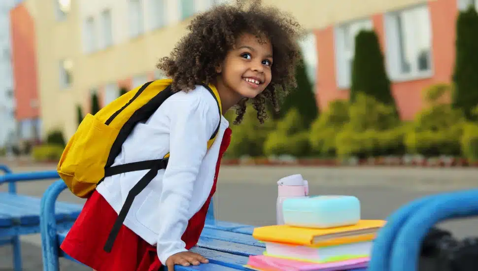 A little girl with school supplies.