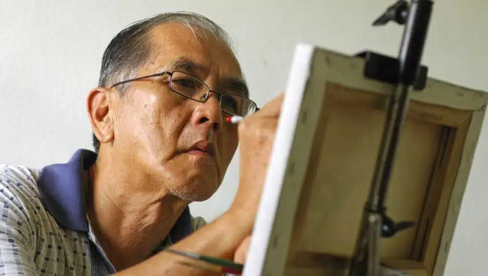 A resident of Freedom Village at Brandywine paints at an easel.