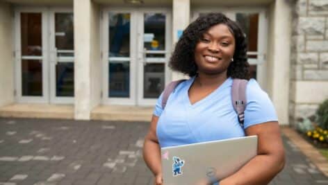 Manor College nursing student standing in front of academic building.