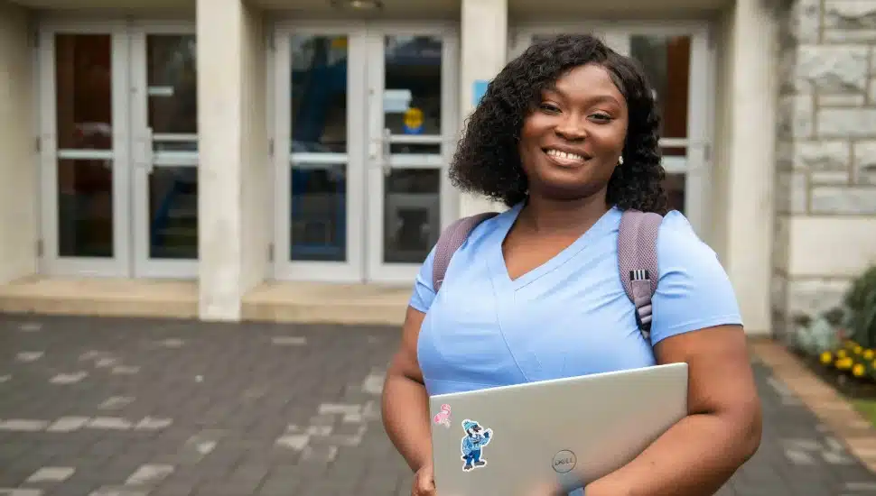 Manor College nursing student standing in front of academic building.