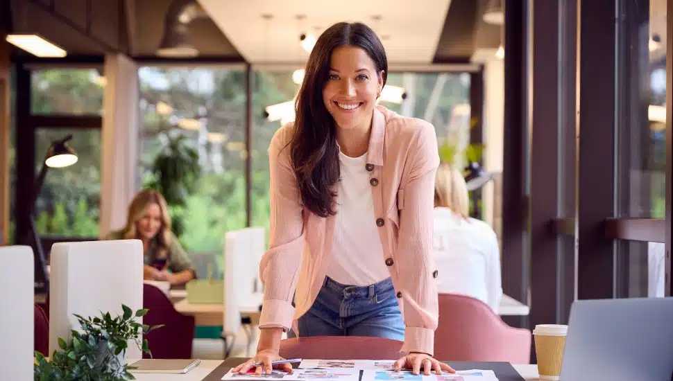 Portrait Of Businesswoman At Table In Office Approving Or Checking Proofs Or Design Layouts.