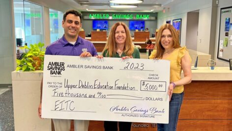 Three people holding a large bank check