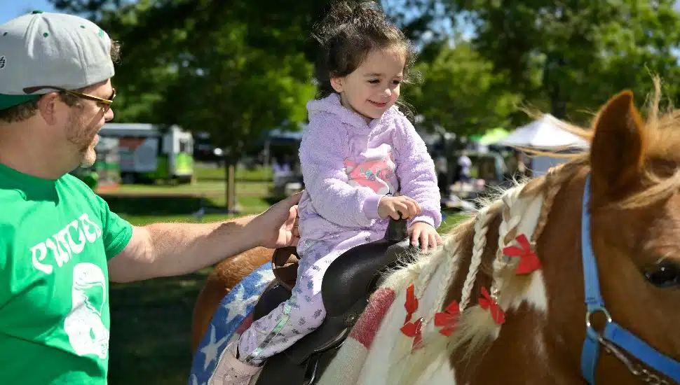 young child riding horse with parental figure in tow