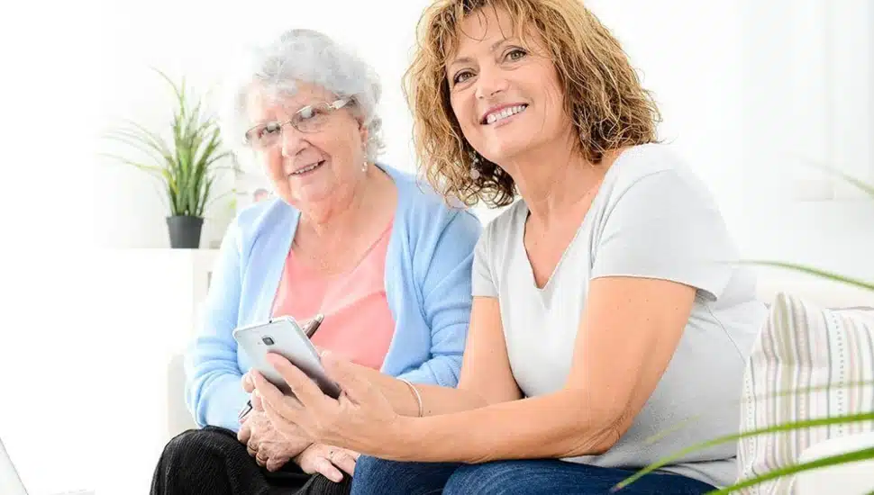 An elderly woman getting help by a middle-aged woman.