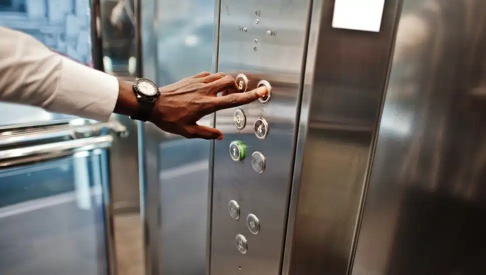 Man's hand selects his floor in an elevator.