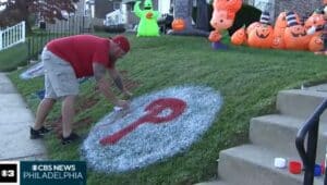 Drexel Hill artists Sea Carey paints the Phillies logo on his front lawn.