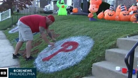 Drexel Hill artists Sea Carey paints the Phillies logo on his front lawn.