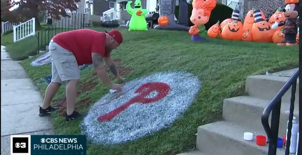 Drexel Hill artists Sea Carey paints the Phillies logo on his front lawn.