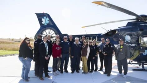 Attendees of the helipad opening celebration standing in front of a helicopter.