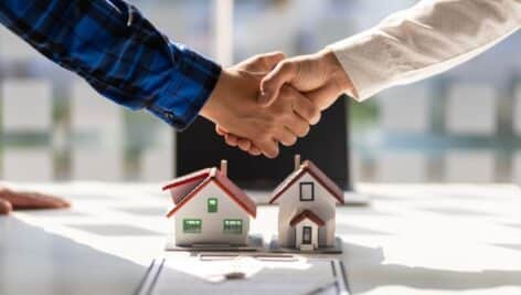 Two people shaking hands on a real estate deal.