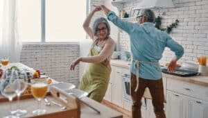 A senior couple dancing in the kitchen.