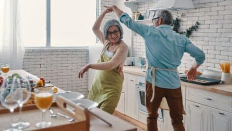A senior couple dancing in the kitchen.